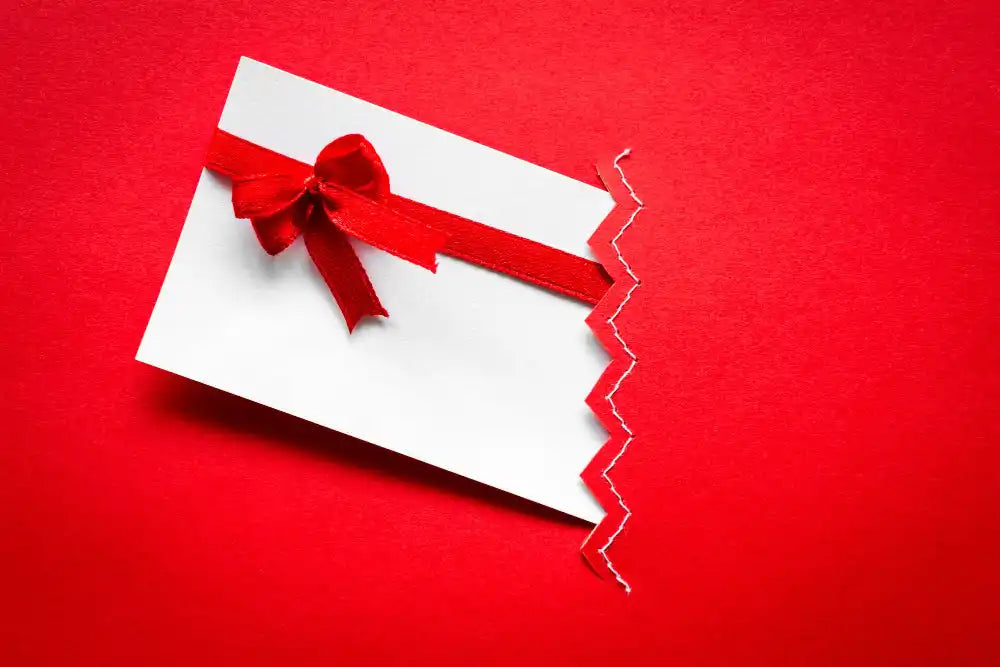 Un buono regalo o una carta bianca con un nastro rosso e un fiocco.